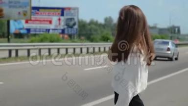 一位年轻漂亮的黑发女人试图在路上不再路过汽车，看上去很沮丧